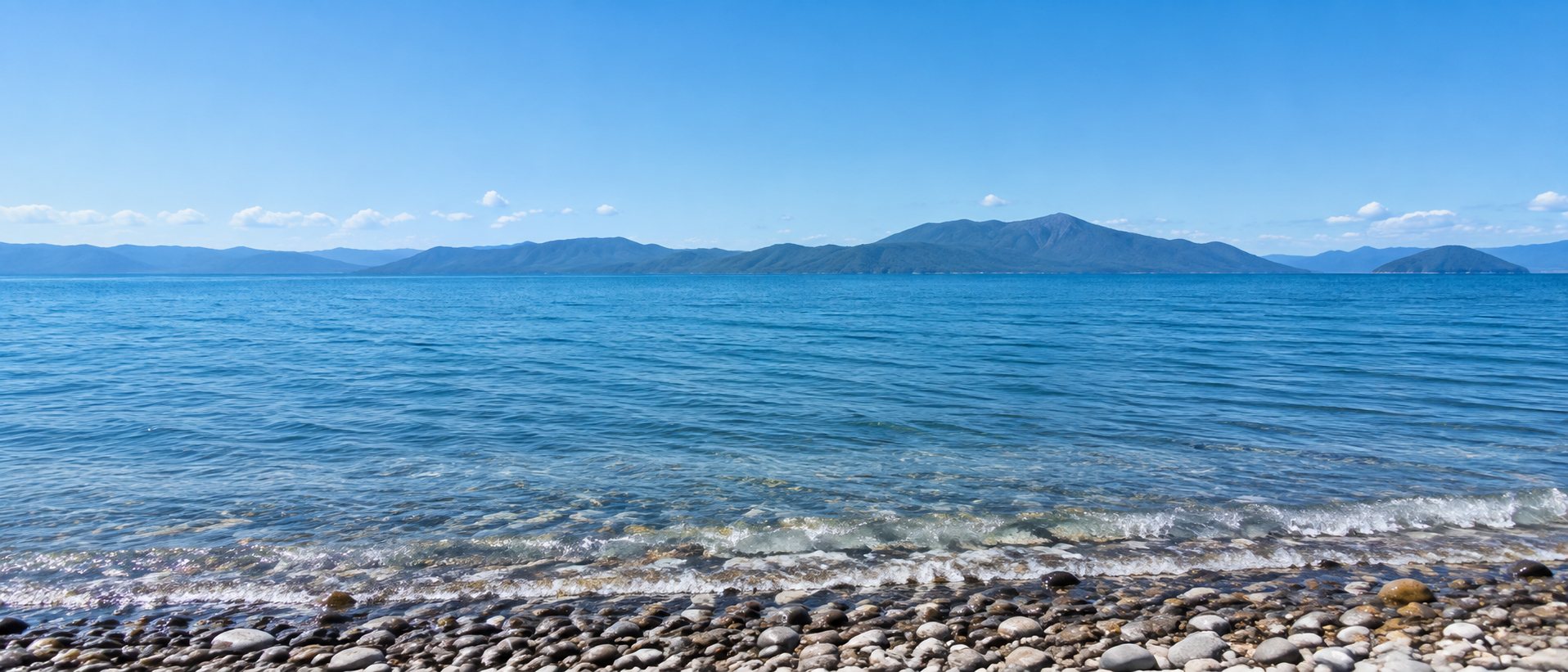 晴れた日の穏やかな噴火湾と、遠くの山並み（掲載イメージ）