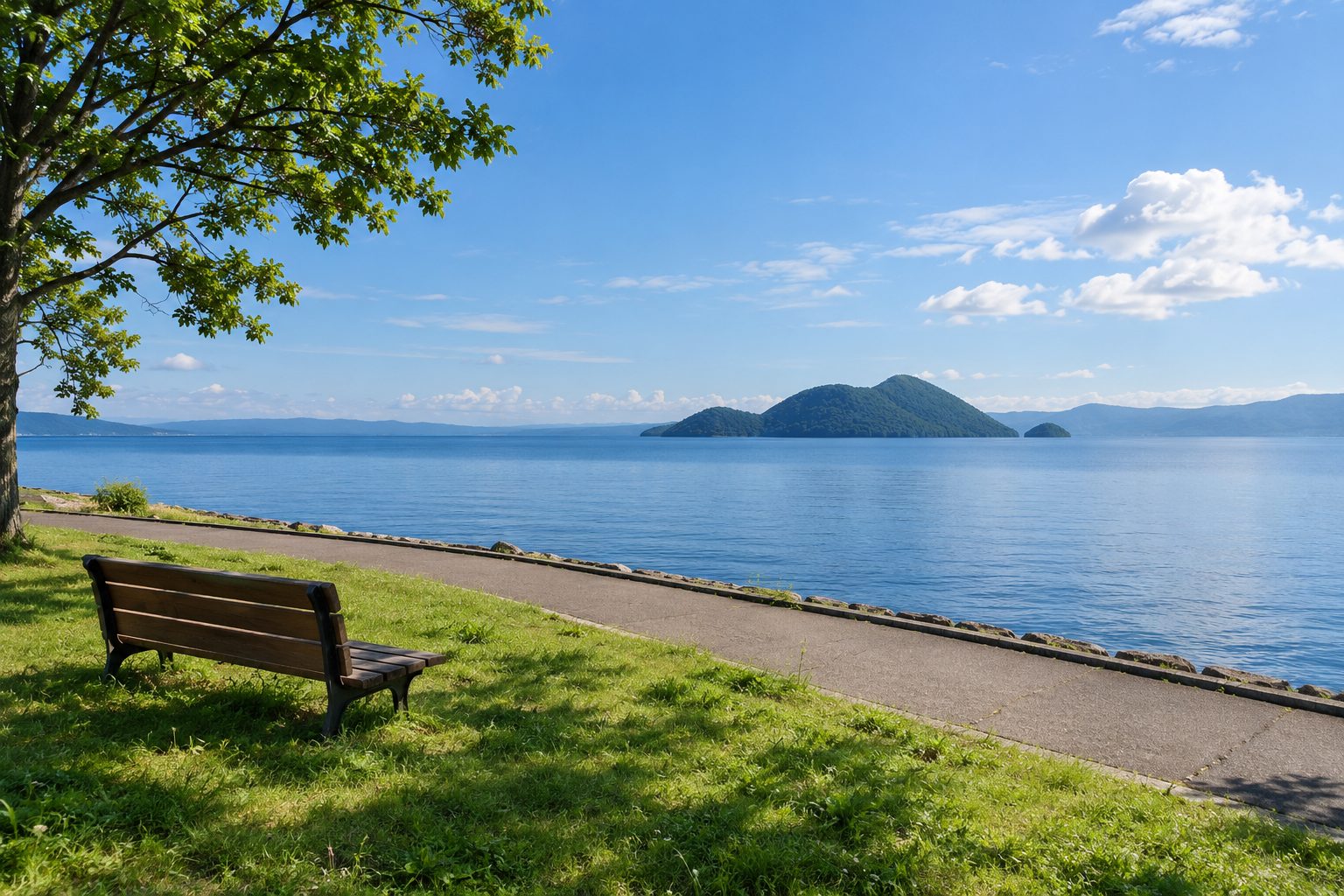 穏やかな湖と、芝生の湖畔の遊歩道